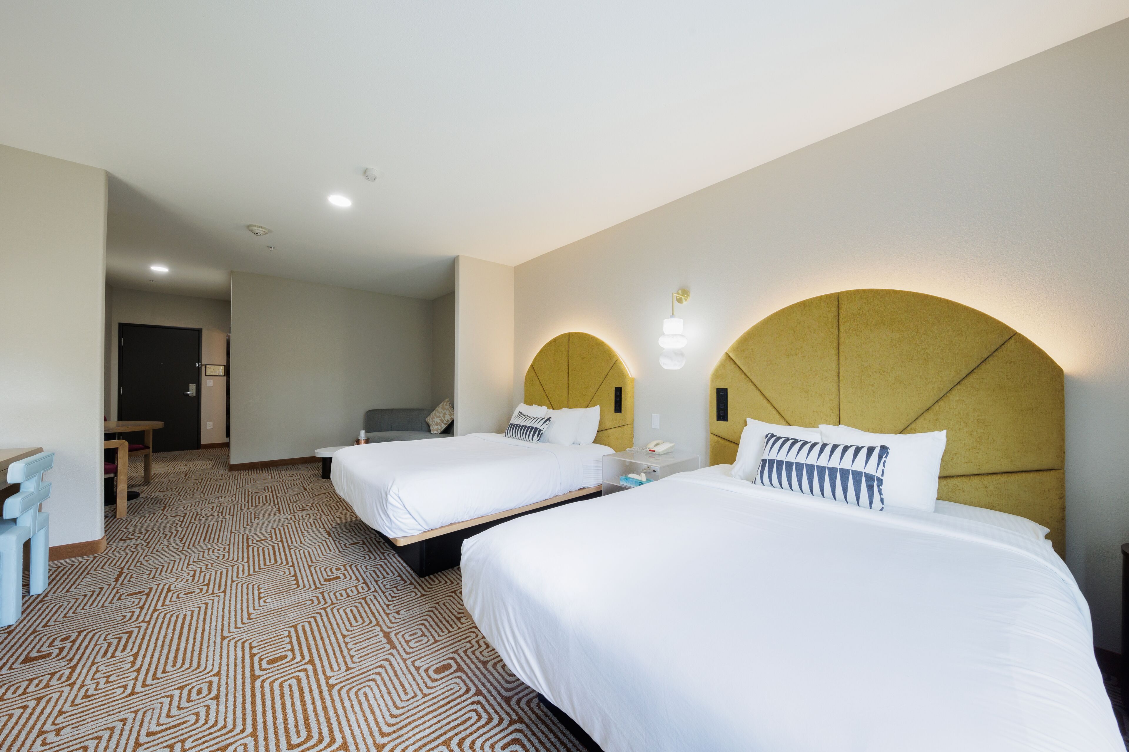 Habitación de hotel con dos camas, un escritorio y una silla.