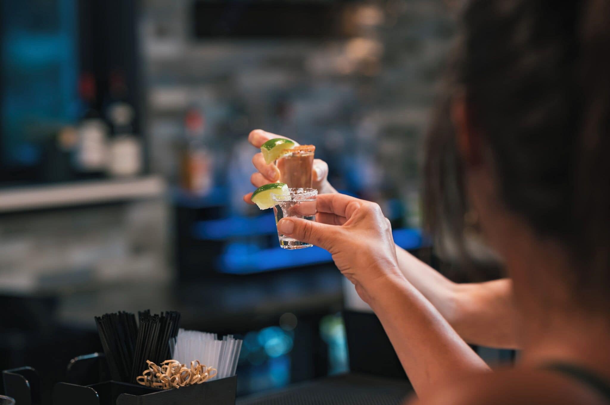 A person holding a drink with a lime wedge.