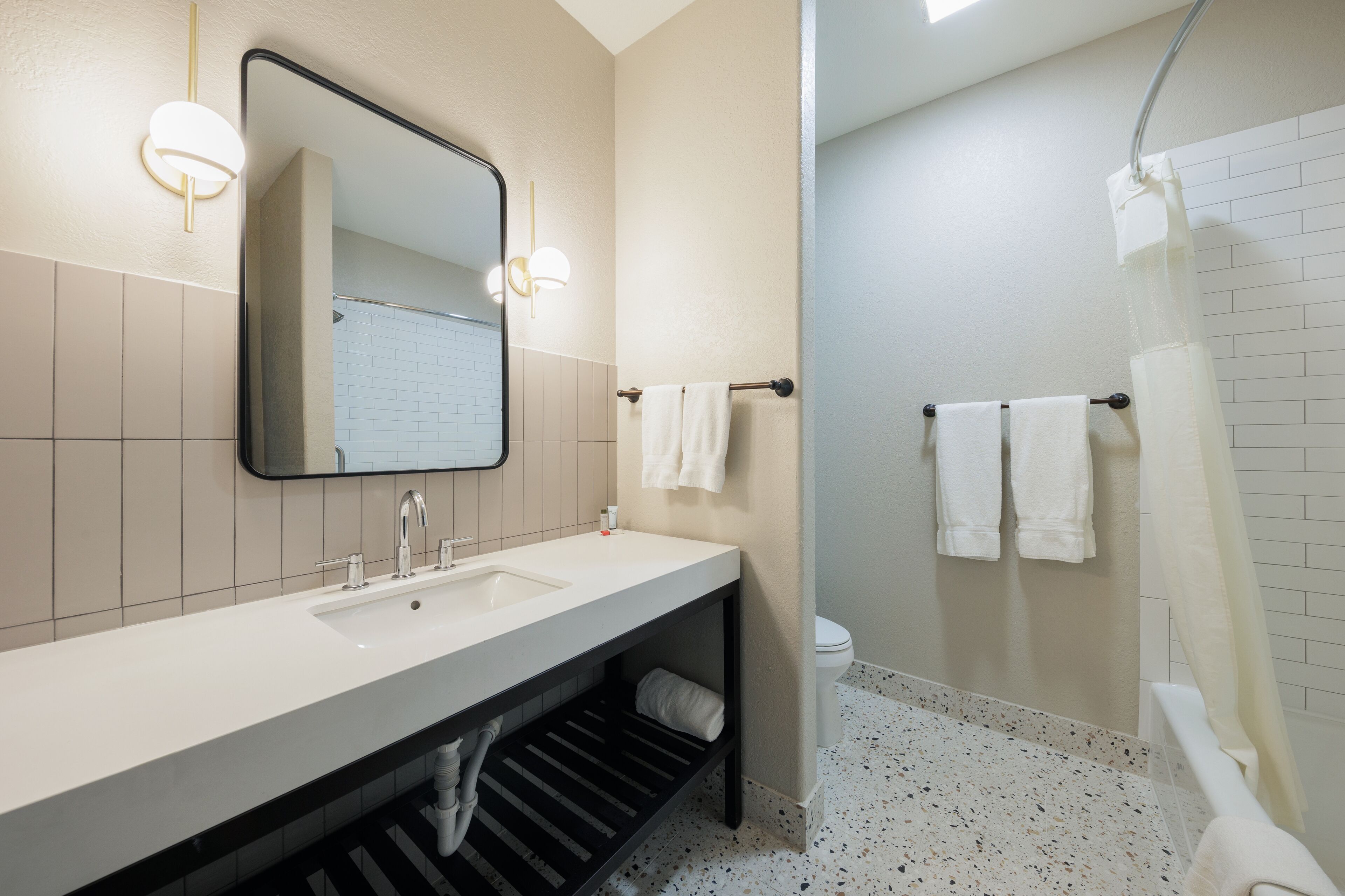 A modern bathroom with a double sink, a large mirror, and a shower area.