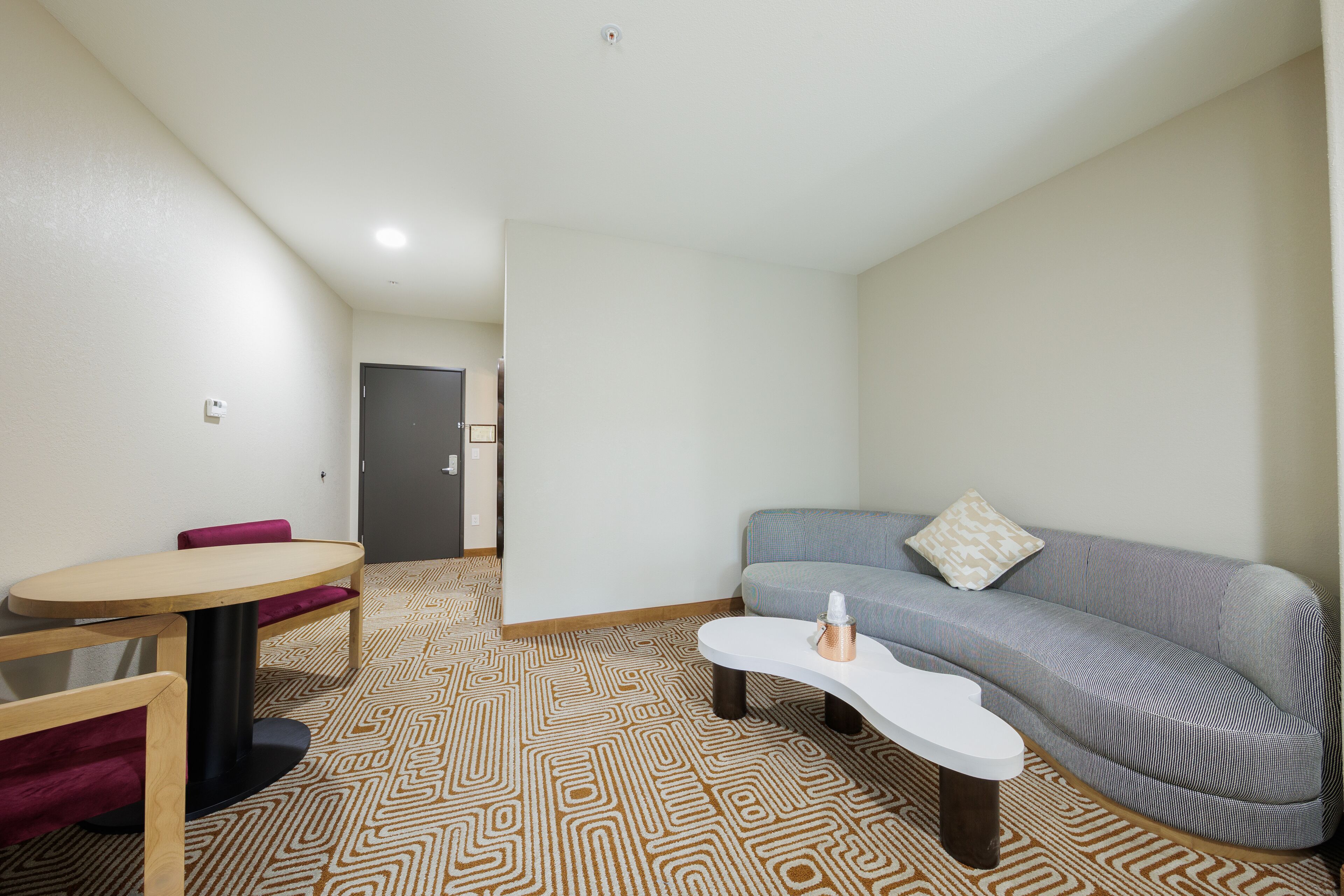 A modern living room with a sofa, a round table, and a patterned carpet.