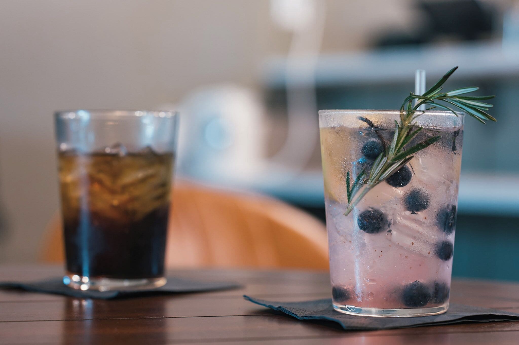 Two glasses of iced beverages on a wooden table.