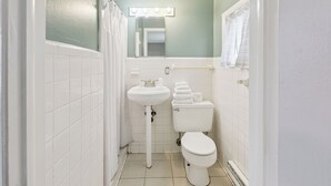A bathroom with a white sink, toilet, and a mirror with lights above. - Curry’s Motel by OYO Saginaw MI (Saginaw)