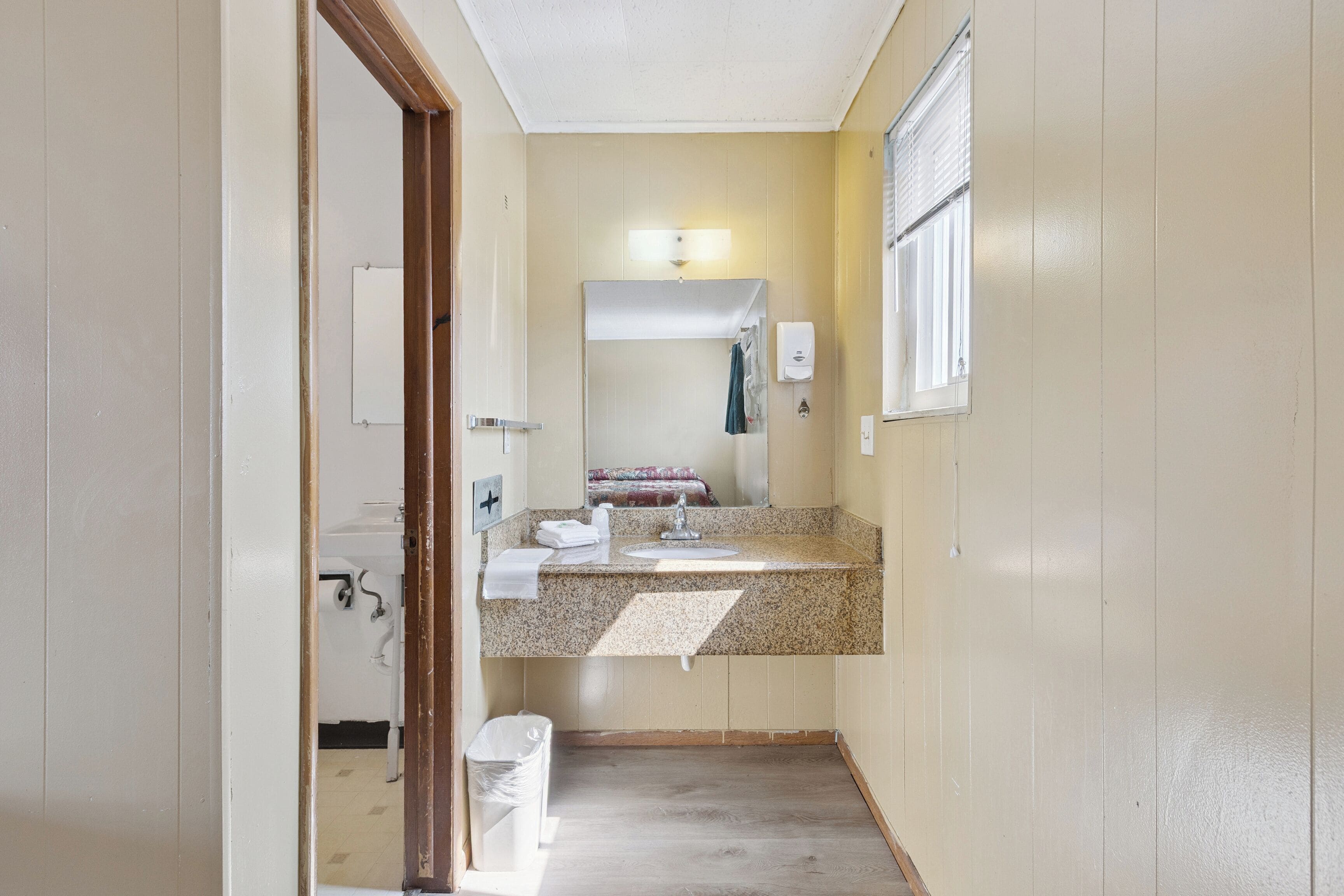 Un baño estrecho con lavamanos, espejo y perchero.