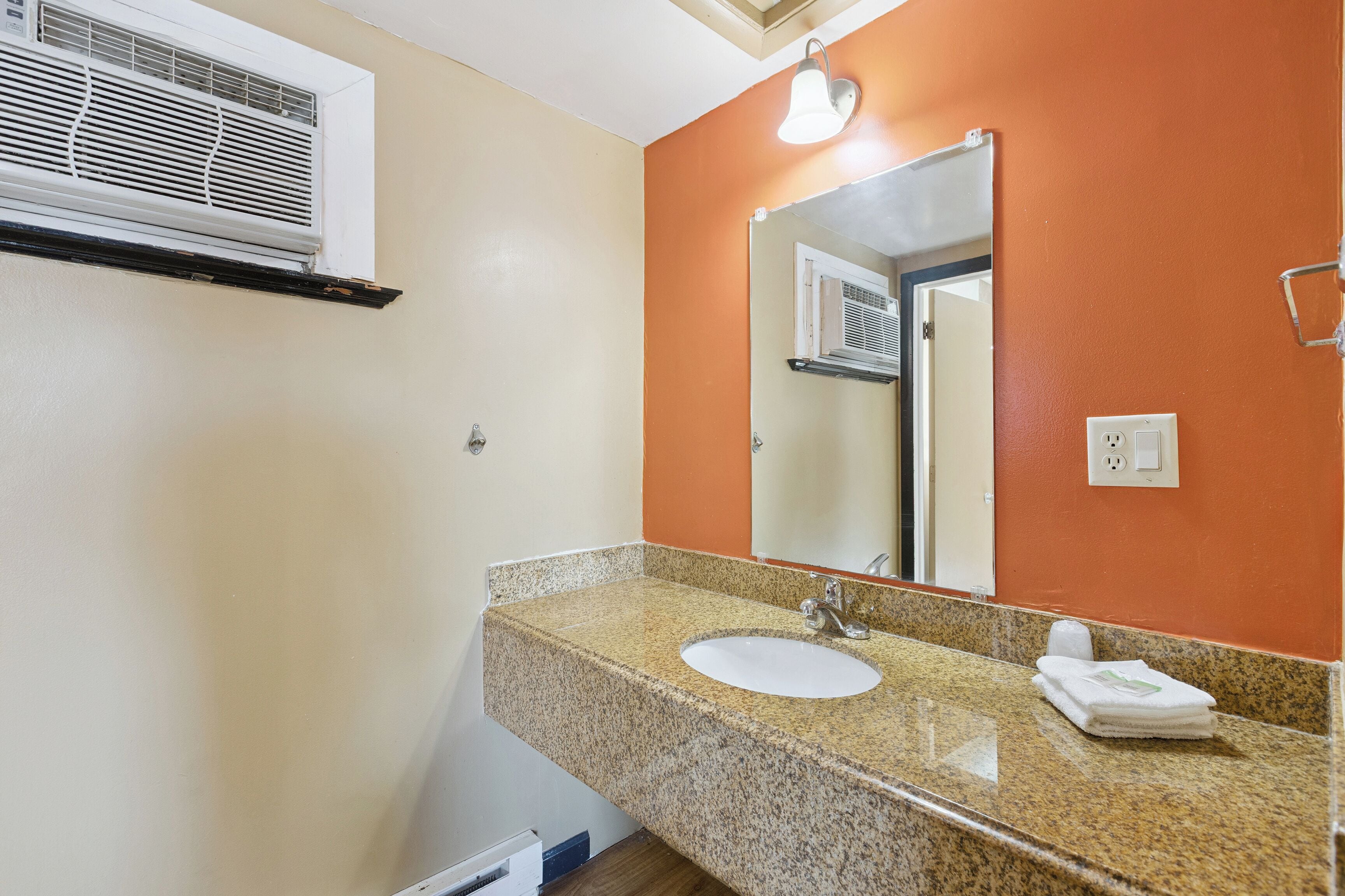 A bathroom with a granite countertop, white sink, and a mirror.