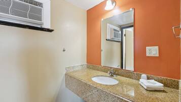 A bathroom with a granite countertop, white sink, and a mirror.
