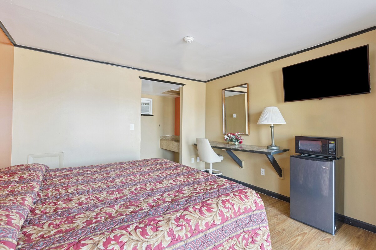 Une chambre d’hôtel équipée d’un lit, d’un bureau, d’une chaise, d’une télévision, d’un four à micro-ondes et d’un miroir.