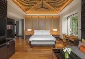 Habitación de hotel moderna con una cama grande, mesitas de noche, un escritorio y vistas al verdor.