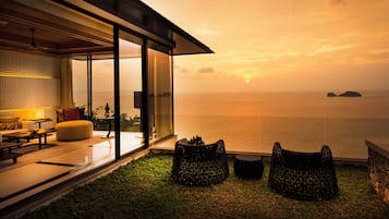 Un salón moderno con un amplio ventanal que da a un balcón con vistas al mar.
