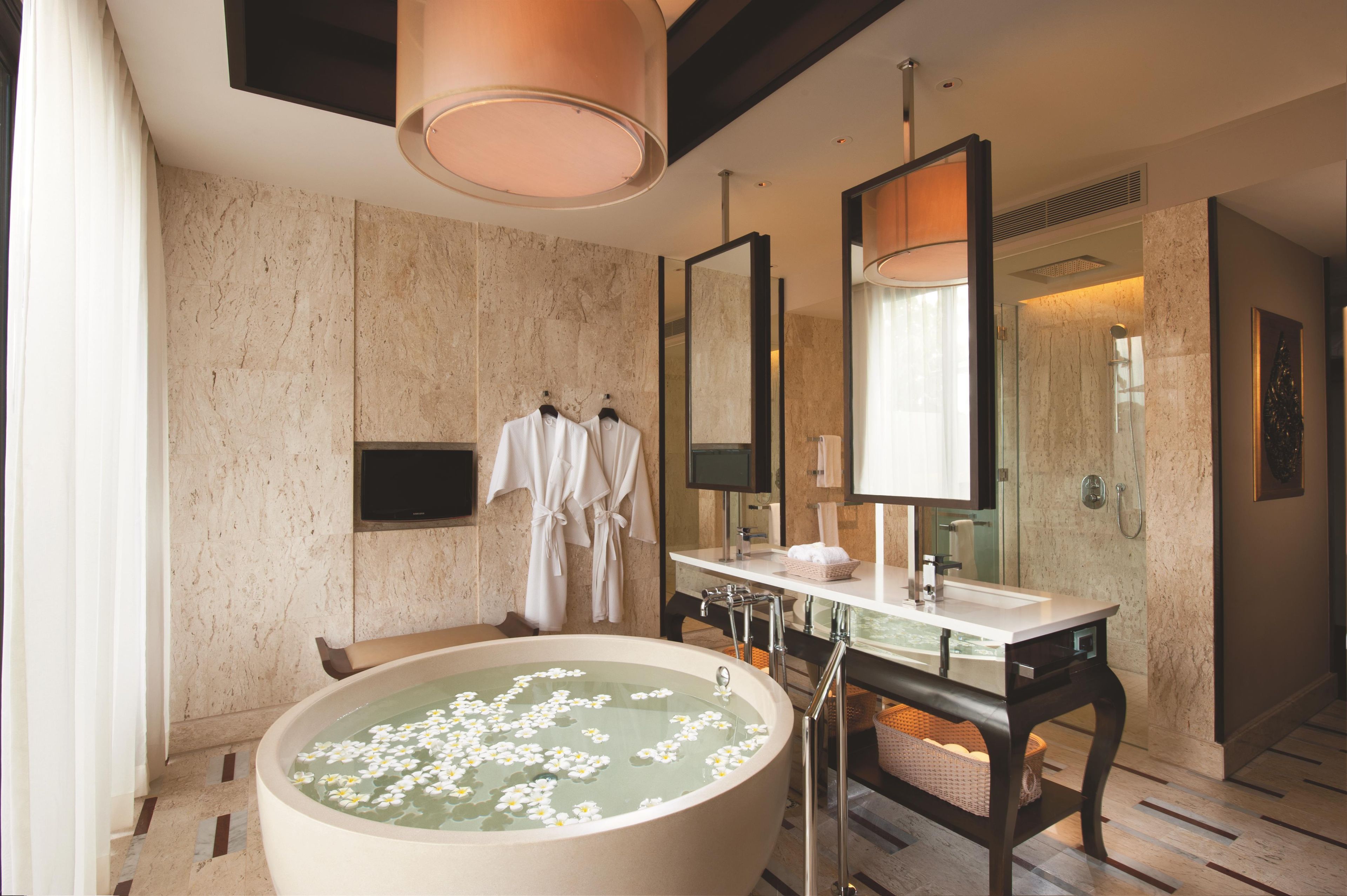 A modern bathroom with a large bathtub, a vanity with a mirror, and a shower area.