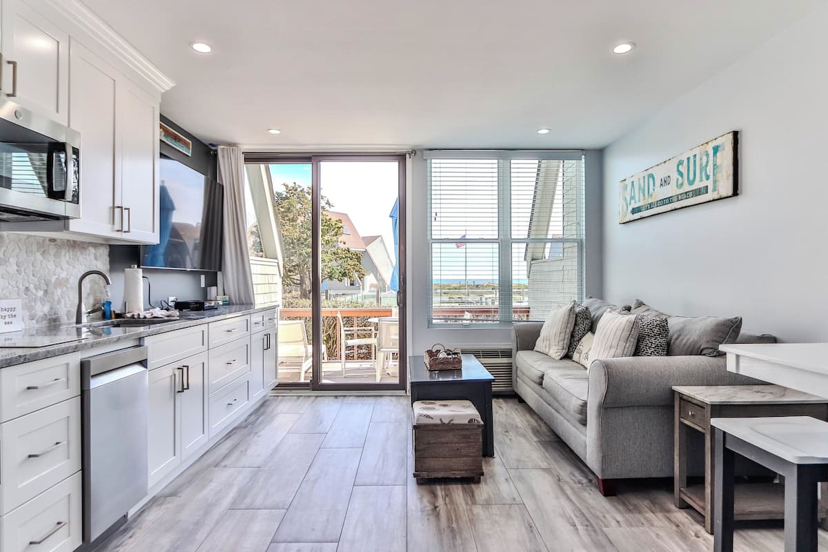 A modern kitchen with white cabinets, a built-in microwave, and a large window.