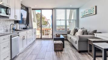 A modern kitchen with white cabinets, a built-in microwave, and a large window.