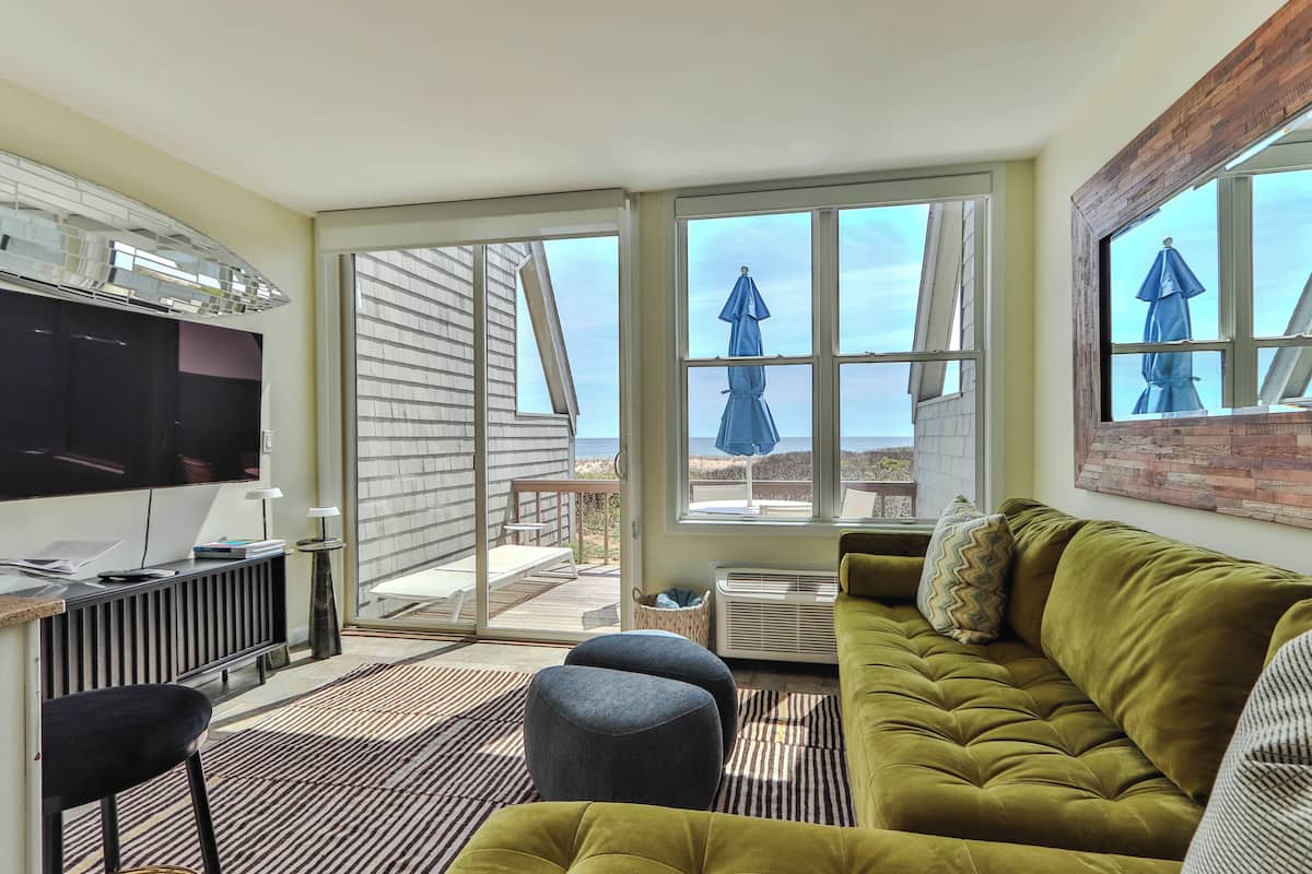 A modern living room with a sofa, a TV, and a dining area with a table and chairs.