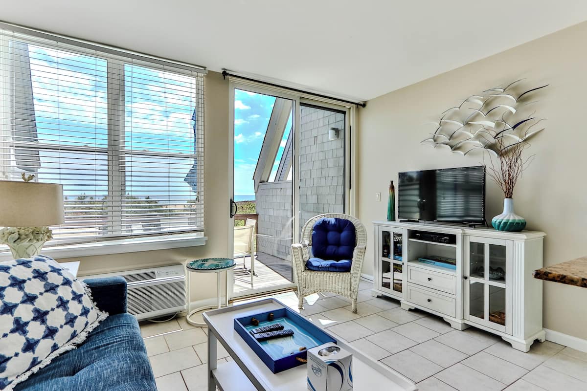 A living room with a sofa, a coffee table, a television, a cabinet, and a chair.