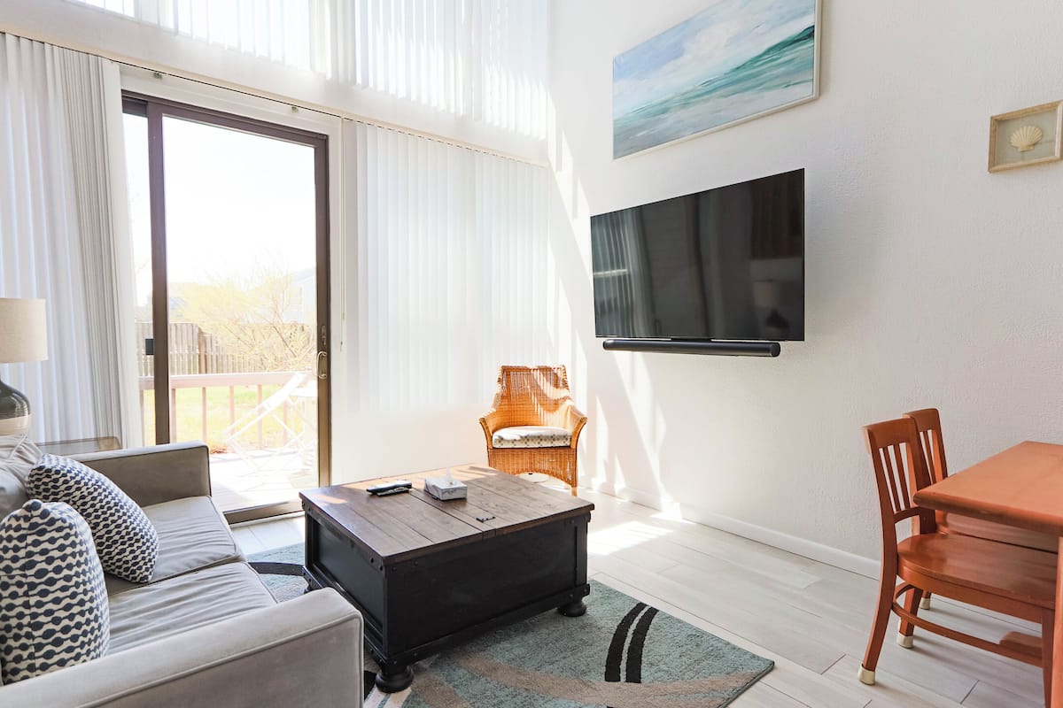 A living room with a sofa, coffee table, TV, and dining table.