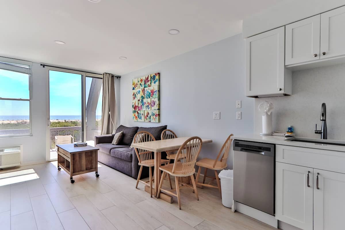 A modern living space with a dining area, kitchen, and large windows offering a view.