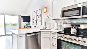 Eine moderne Küche mit weißen Schränken, einem eingebauten Geschirrspüler, einer Edelstahl-Mikrowelle und einem Backofen.