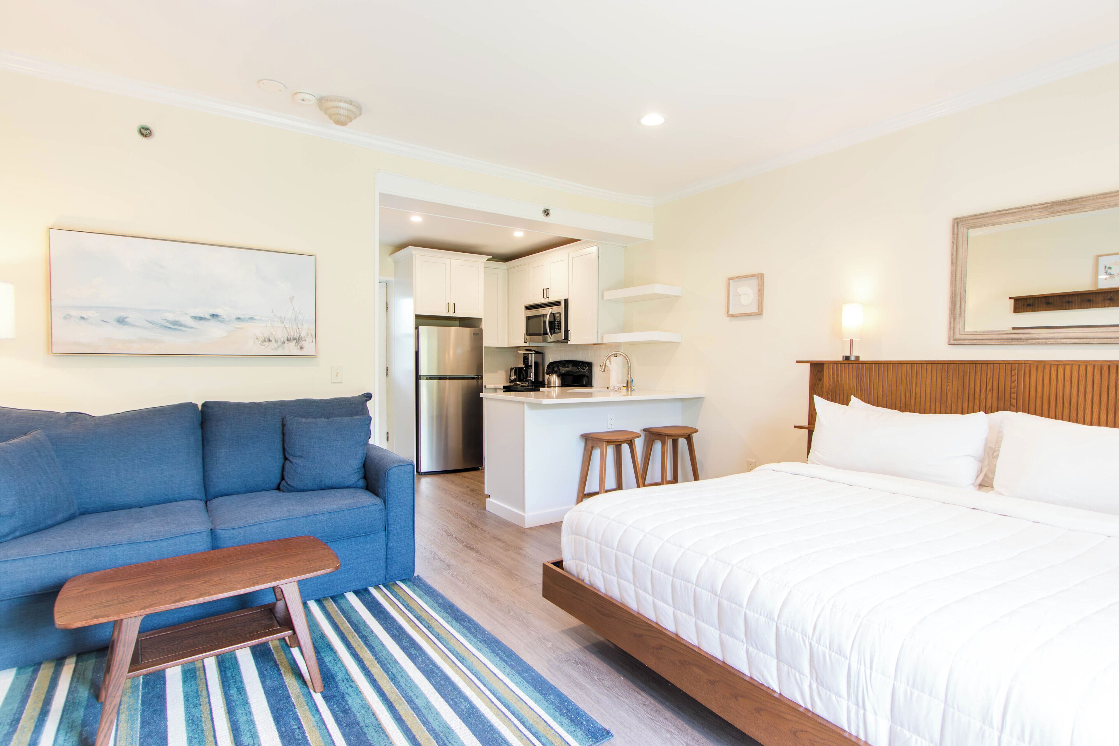 Une chambre d’hôtel moderne avec un canapé, un lit, un coin cuisine et une vue sur l’océan.