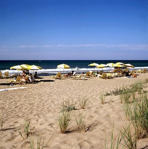Na praia, espreguiçadeiras, guarda-sóis, toalhas de praia 