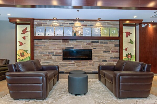 Una sala de estar con chimenea de piedra, sofás de cuero y un televisor de pantalla plana.