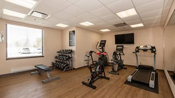Een sportschool met fitnessapparatuur, een bank en een televisie aan de muur.