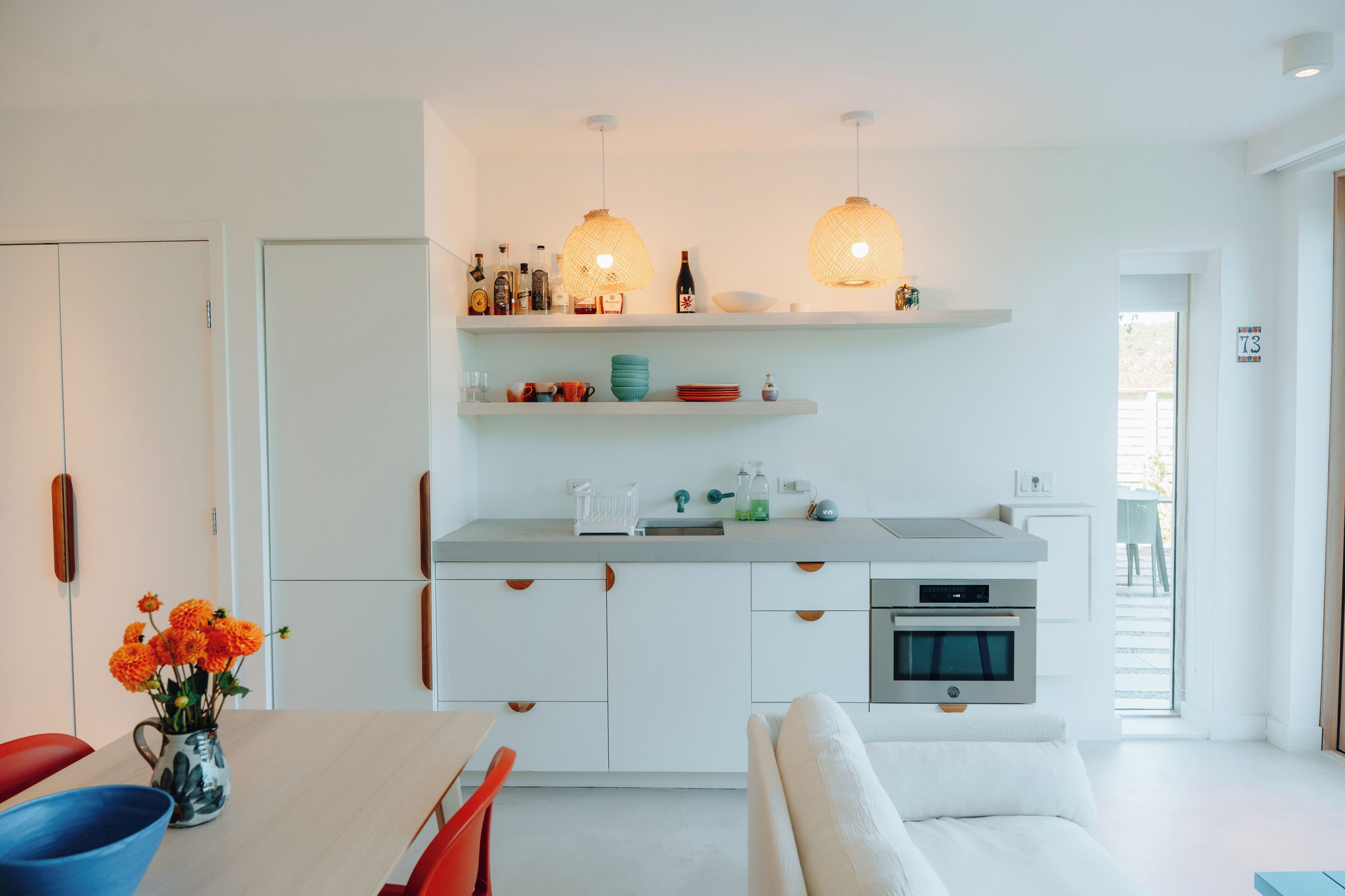 Una cocina moderna con armarios blancos, un comedor con mesa y sillas, y vistas al exterior.