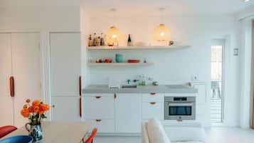 Une cuisine moderne avec des meubles blancs, un coin repas comprenant une table et des chaises, et une vue sur l’extérieur.