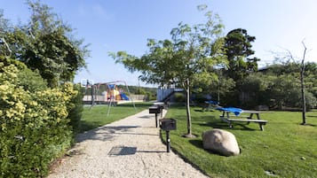 Explore a serene park setting with a playground, picnic area, and scenic trees.