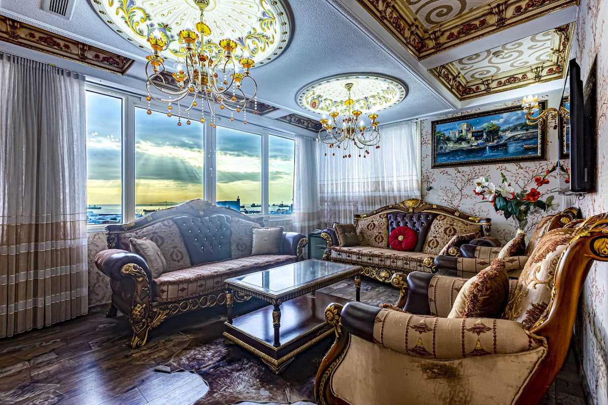 Un salón lujoso con muebles ornamentados, una gran lámpara de araña y una vista panorámica a través de las ventanas.