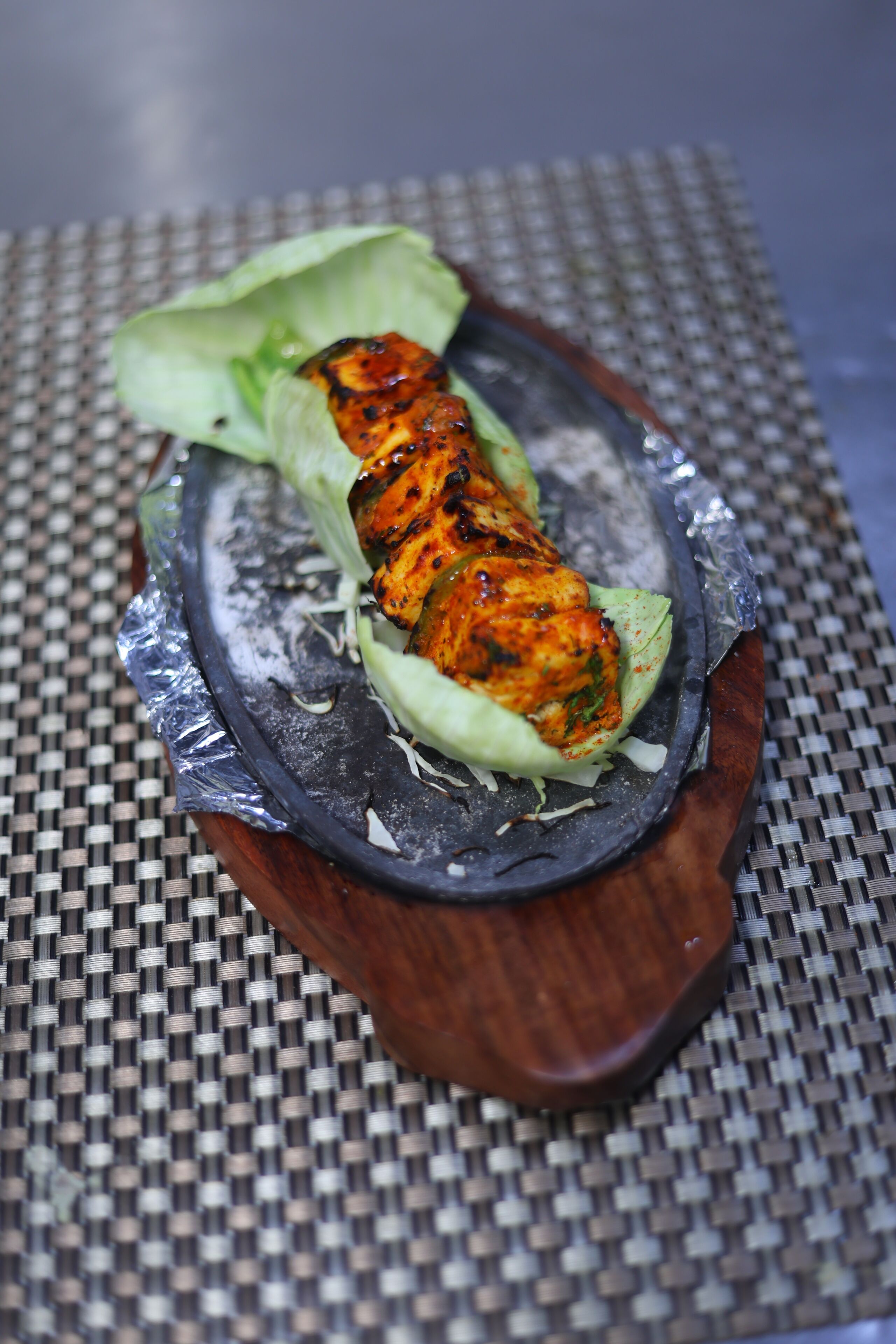 A grilled chicken dish on a woven mat.