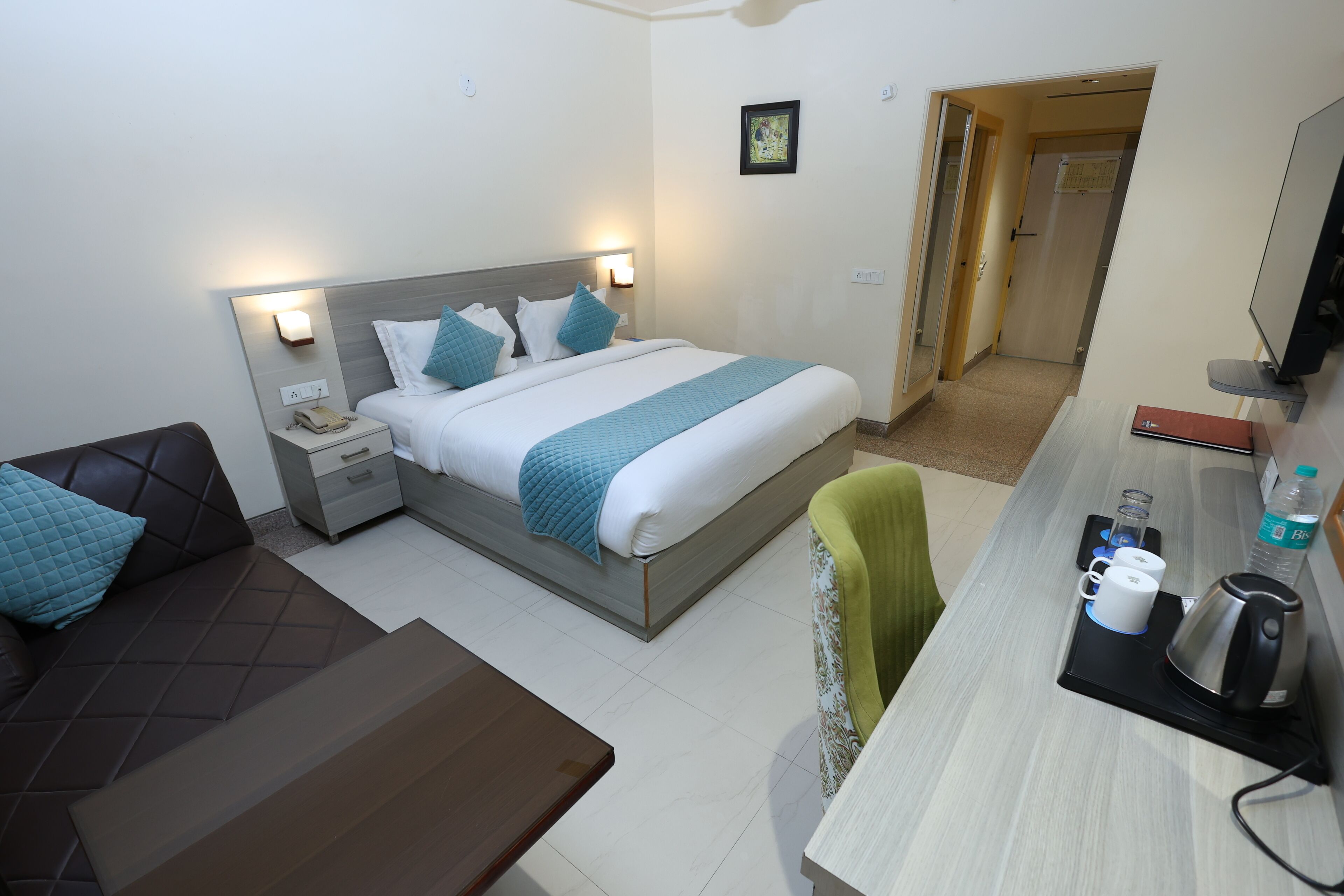 A hotel room with a bed, bedside tables, a desk, a chair, and a television.