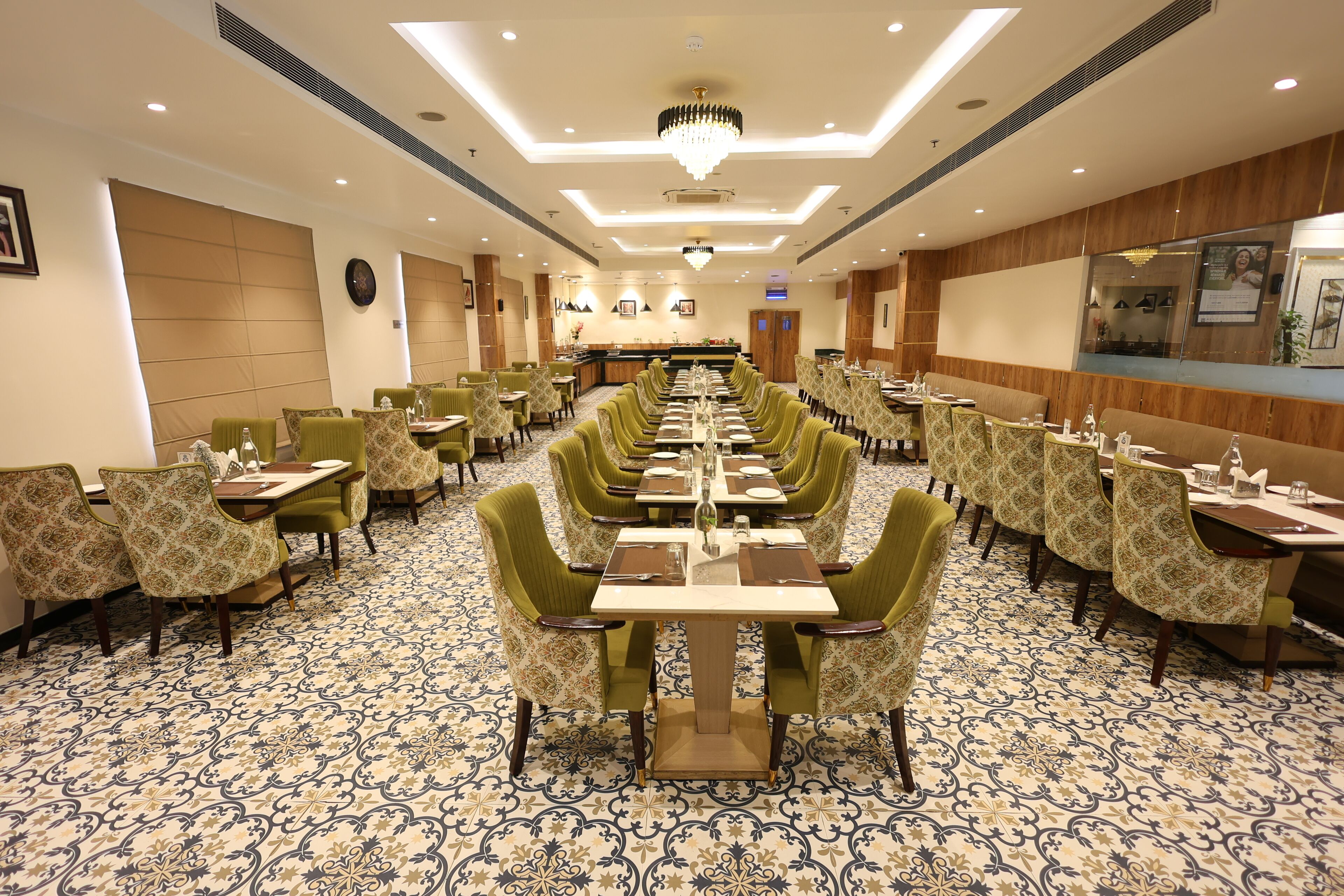 Un comedor de hotel con mesas largas, sillas estampadas en verde y una alfombra con diseño.