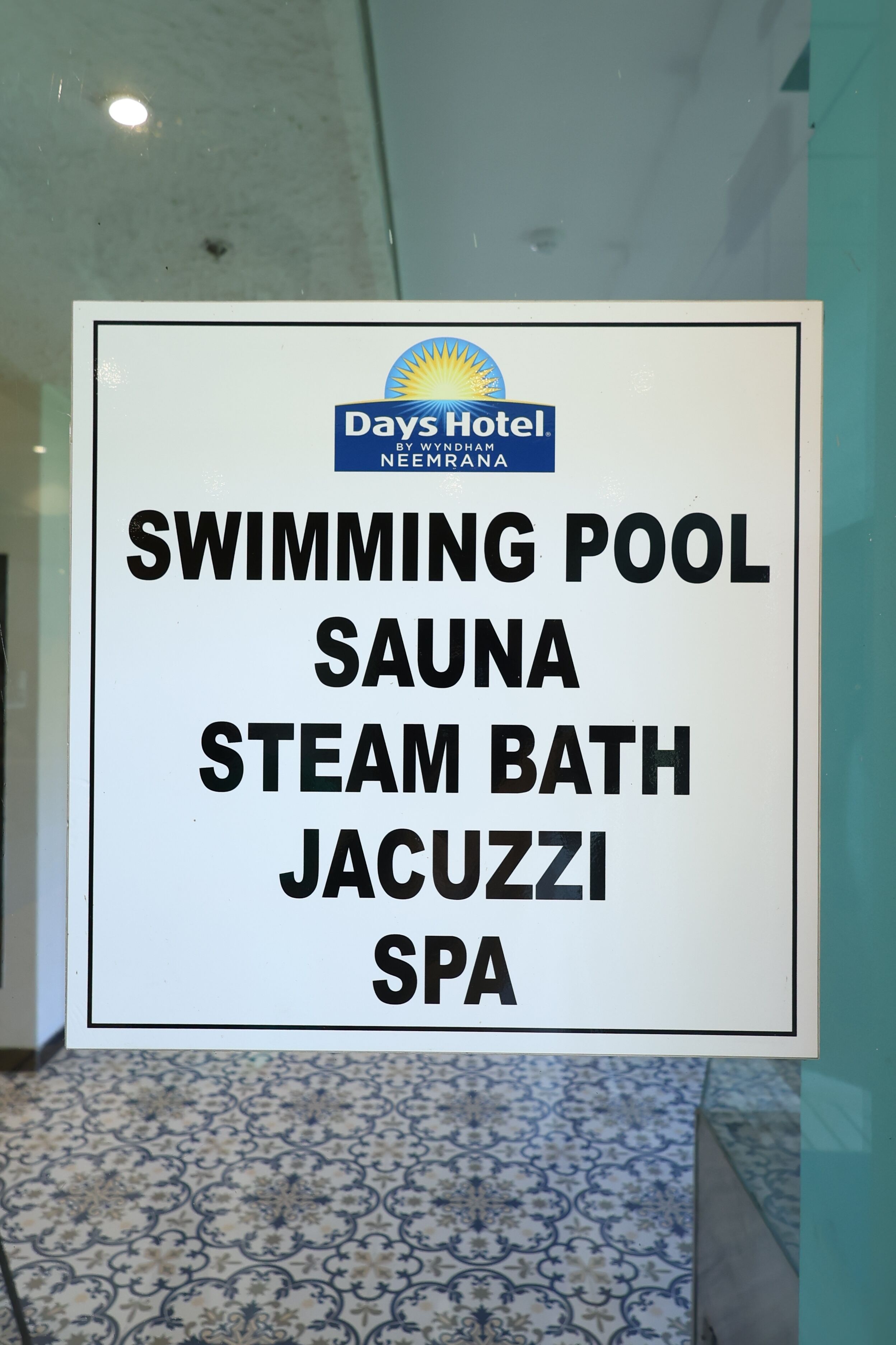 Letrero que enumera los servicios, que incluyen piscina, sauna, baño de vapor, jacuzzi y spa en Days Hotel by Wyndham en Neemrana.