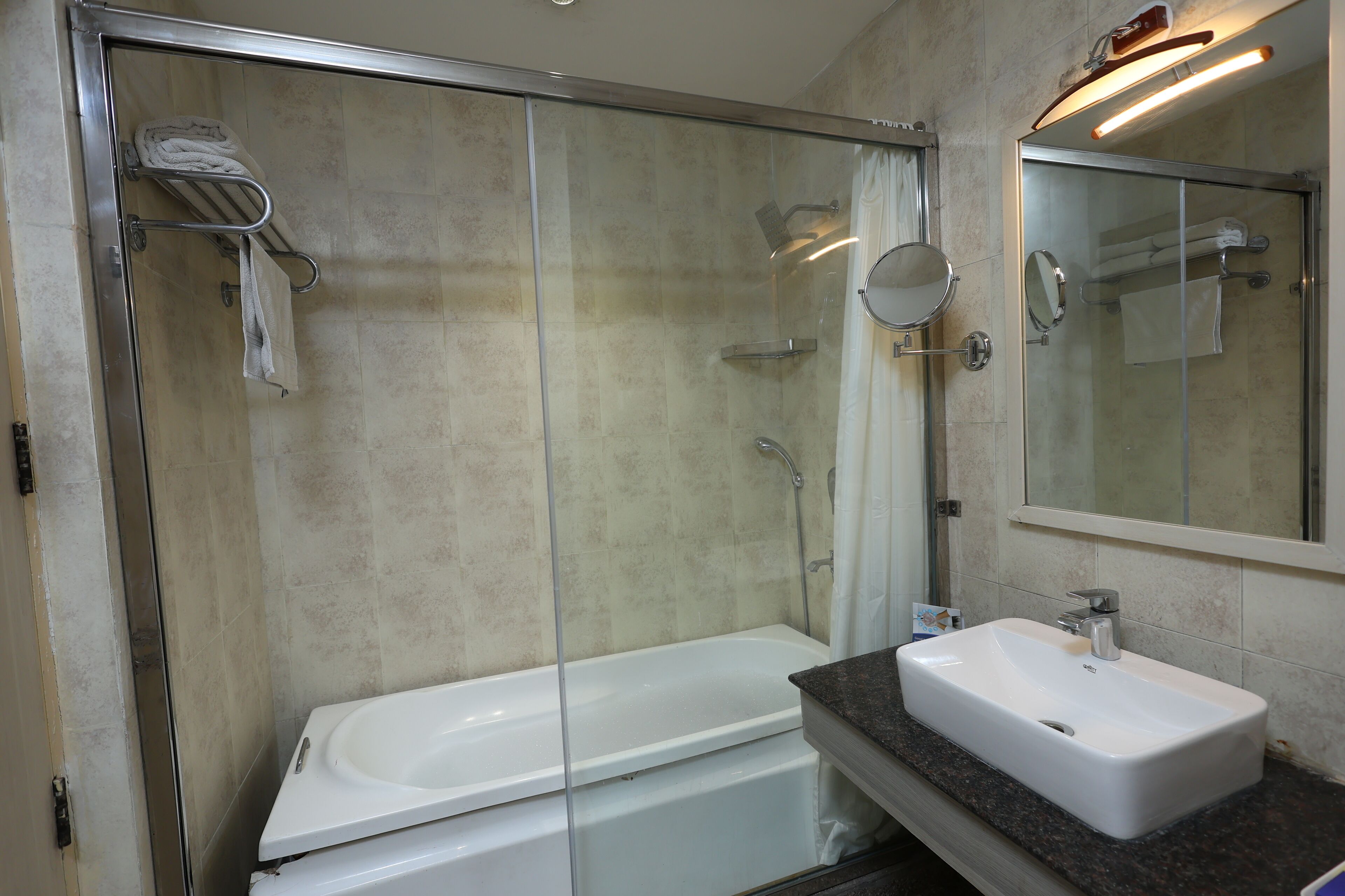A modern bathroom with a glass-enclosed shower, a white bathtub, and a vanity with a sink.