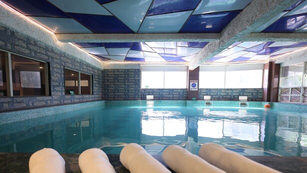 A swimming pool with a tiled ceiling, a brick wall, and a window. - Days Hotel by Wyndham Neemrana Jaipur Highway (Neemrana)
