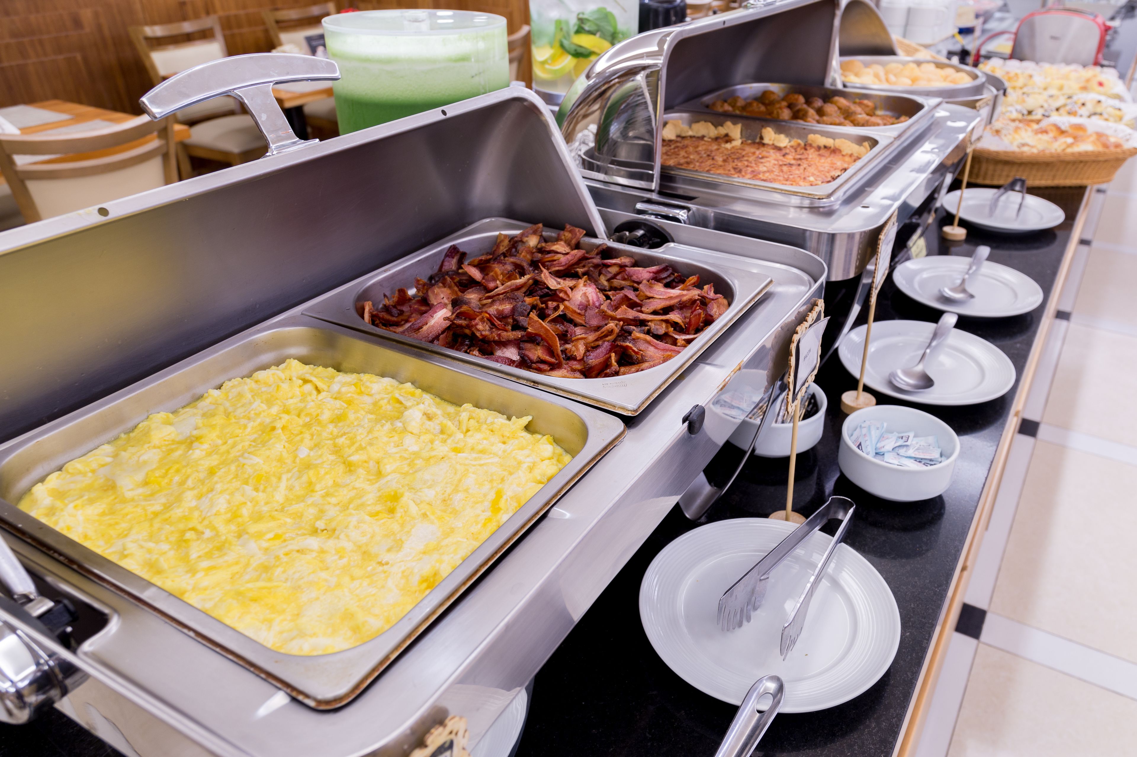 A buffet with various food options including scrambled eggs, bacon, and other dishes.