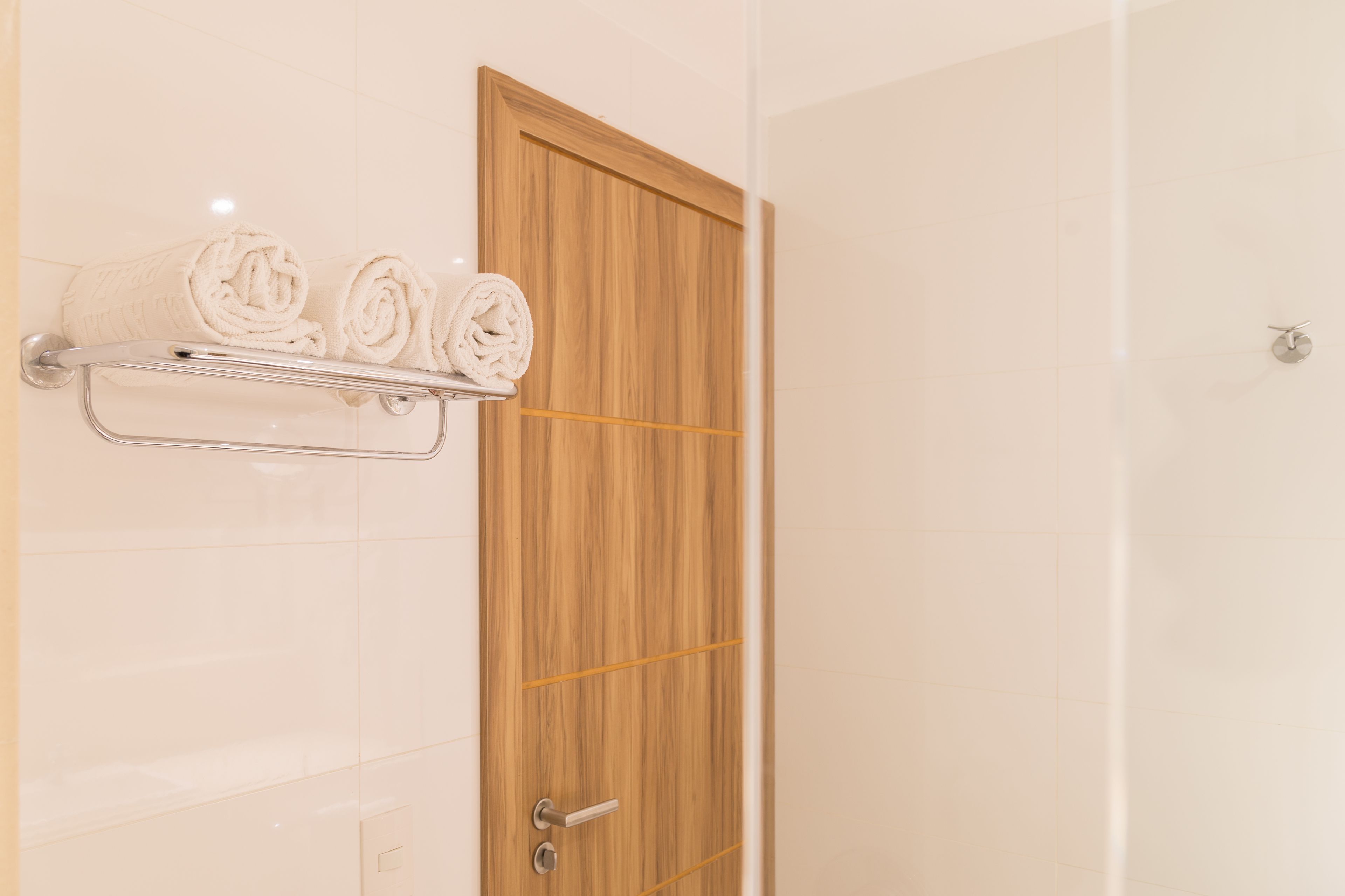 Ein Badezimmer mit Holztür, Handtuchhalter und gerollten Handtüchern sowie einer Duschkabine.
