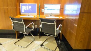 Two computer workstations with chairs, a wooden wall, and a tiled floor.