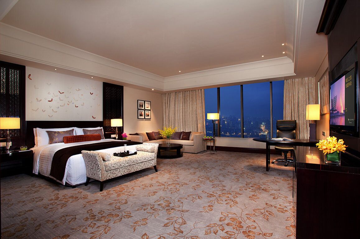 Ein Hotelzimmer mit einem großen Bett, einer Couch, einem Schreibtisch und einem Fernseher.