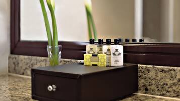 A small, dark brown, rectangular box with a lock on the front, placed on a granite countertop. Inside the box, there are several bottles of hand and body lotion, and a glass with a green plant.