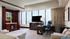 Habitación de hotel con una ventana grande, un televisor de pantalla plana, un escritorio con silla y un sofá.