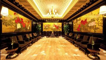 Una sala elegante con una mesa larga, múltiples sillas y pinturas florales en las paredes.