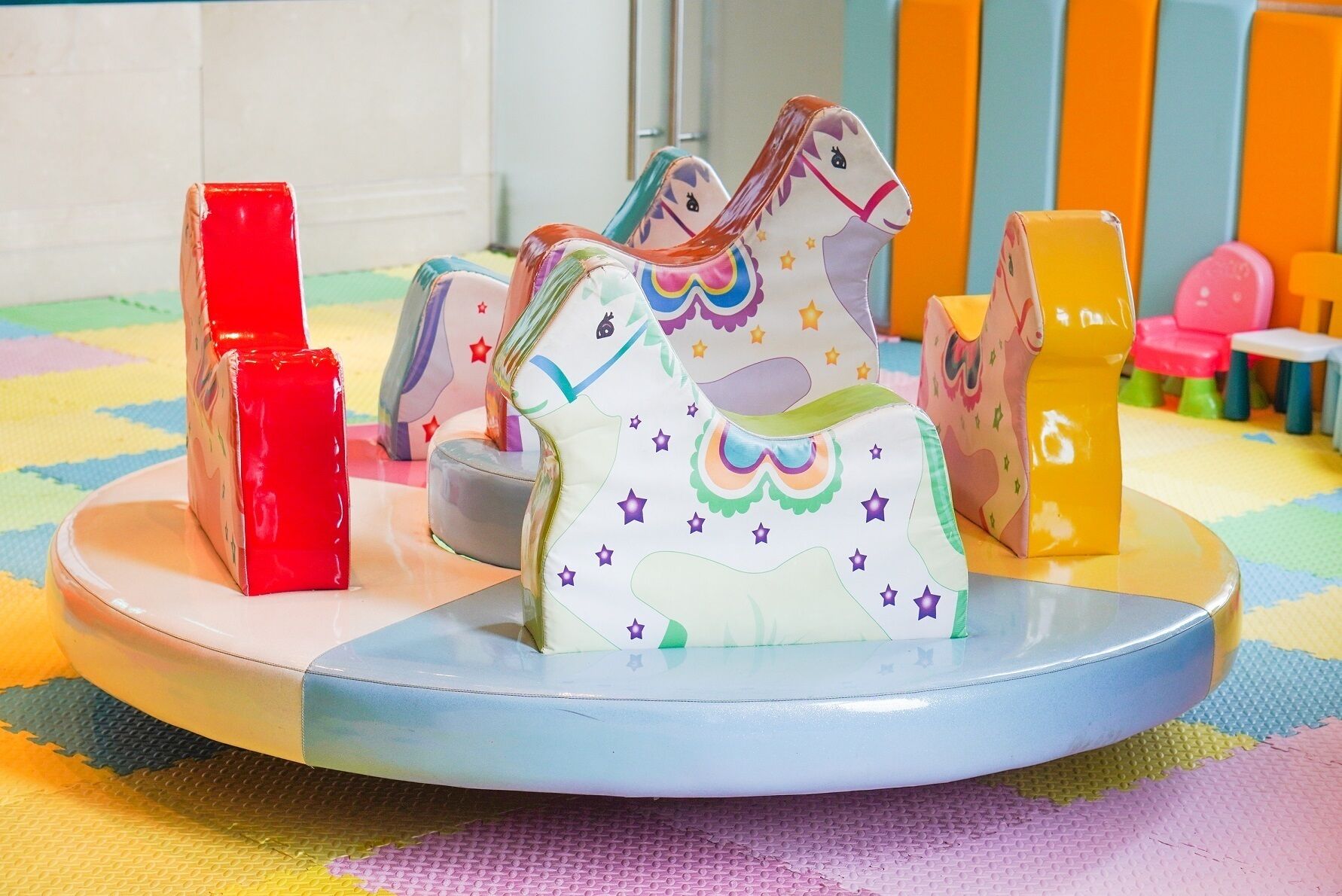 Een kinderspeelplaats met een carrousel, kleurrijk speelgoed en een patroon vloer.