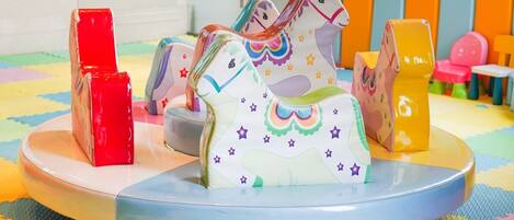 Een kinderspeelplaats met een carrousel, kleurrijk speelgoed en een patroon vloer.