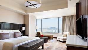 Una habitación de hotel amplia con una cama grande, un sofá, una mesita de centro y un televisor.