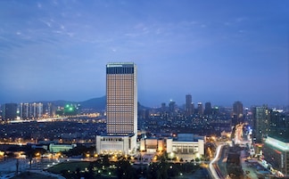 Un hotel moderno de gran altura, rodeado por un paisaje urbano al atardecer.