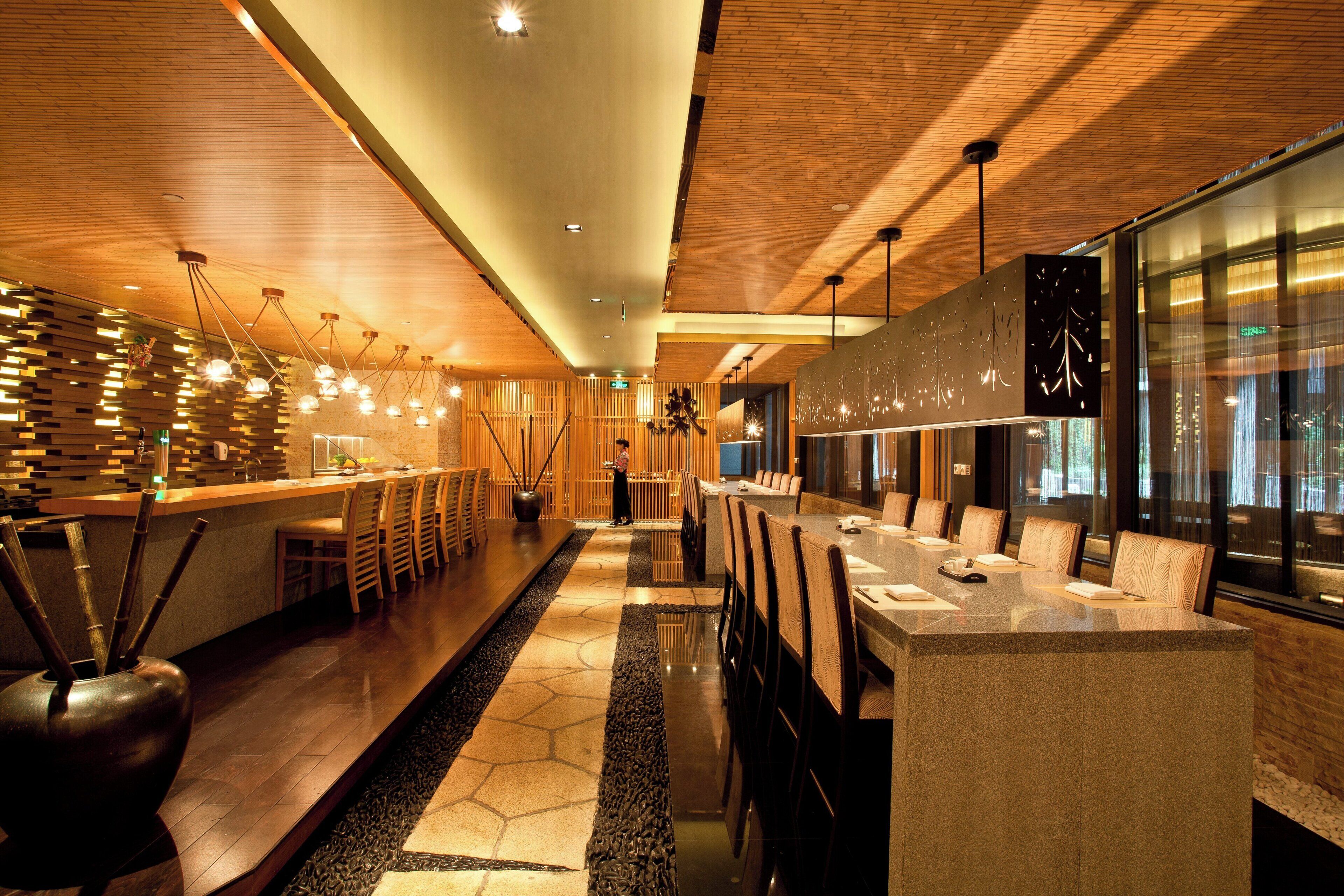 A modern hotel lobby with a long reception desk, seating area, and a large window.