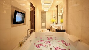 Un baño moderno con una bañera grande, un televisor montado en la pared y un espejo sobre el lavabo.