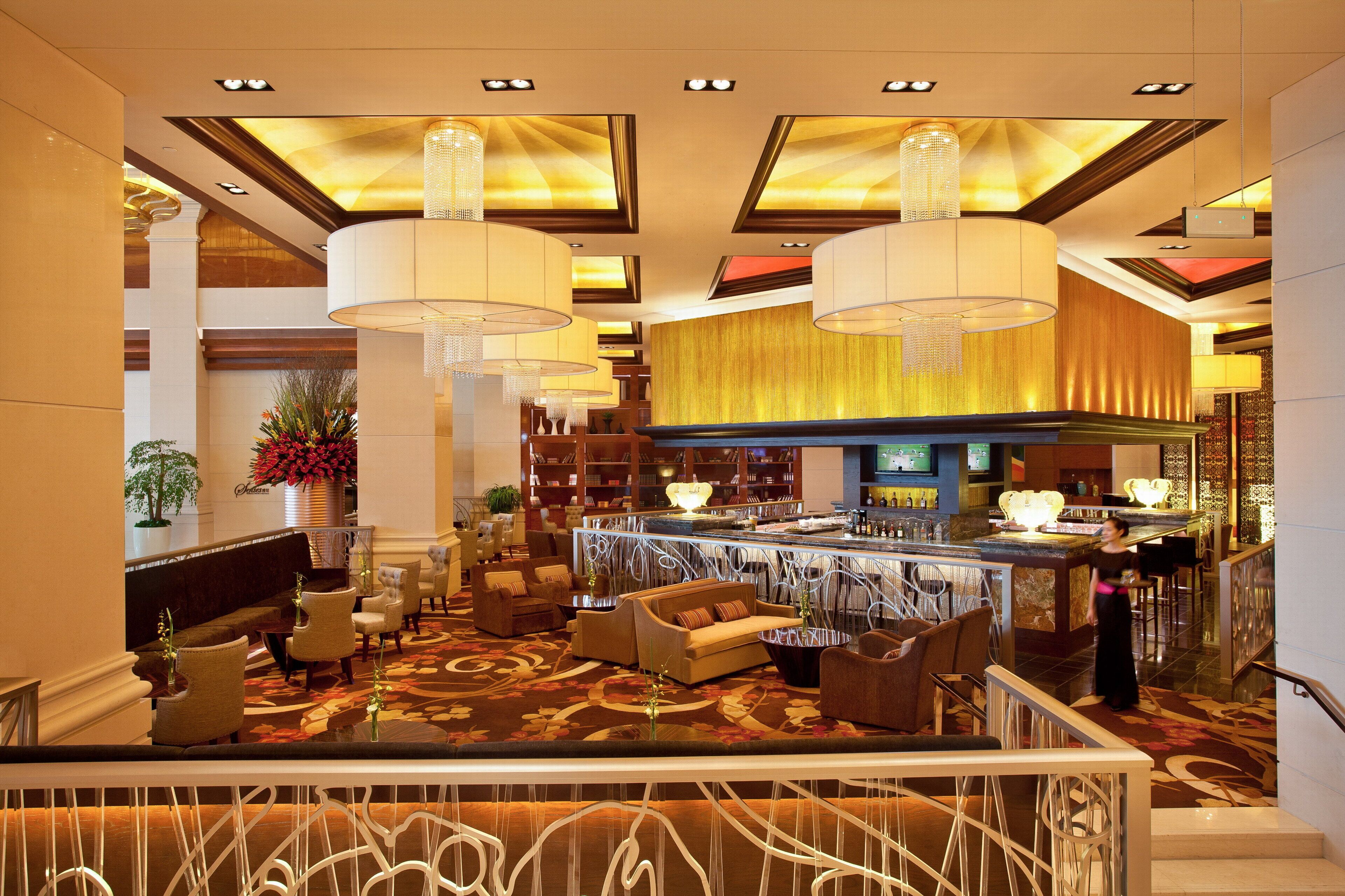 A hotel lobby with a bar area, seating arrangements, and a staircase.