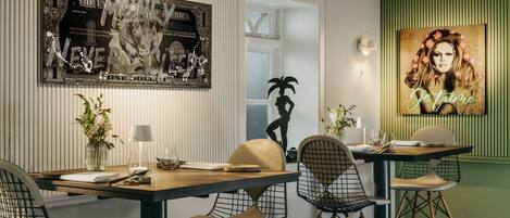 A dining area with a wooden table, wire mesh chairs, and a green accent wall.