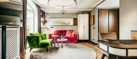A modern living room with a green armchair, a red sofa, a round coffee table, and a dining table.
